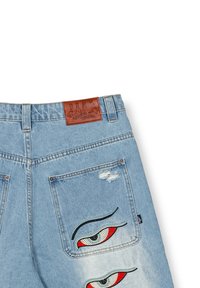 Lichtblauwe denim spijkerbroek met een leren label, voorzien van geborduurde oogontwerpen op de achterzakken en versleten details bij de naden.
