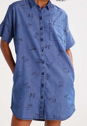 Kort mouw denim jurk met knopen aan de voorkant, uitgevoerd in blauwe stof en zwart omrande illustraties verspreid over de stof. Inclusief een borstzak.