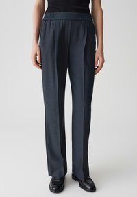 Donkergrijze elastische taillebroek met een losse pasvorm, voorzien van een gladde textuur en rechte pijpen, gecombineerd met zwarte schoenen.