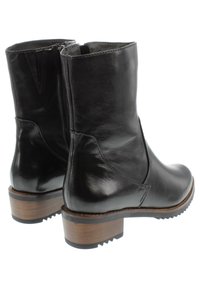 Botas de cuero negras hasta el tobillo con punta redondeada, cremallera lateral y tacón de bloque de madera. Textura suave con sutiles detalles de costura.