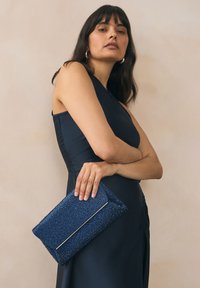Navy blue clutch bag with a textured surface covered in small, sparkling embellishments, featuring a silver-tone accent edge.