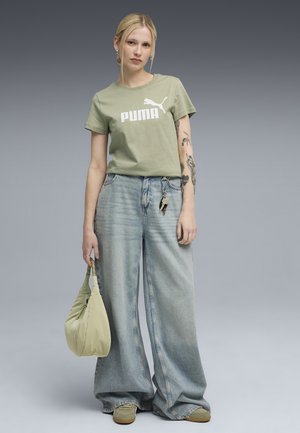 T-shirt in cotone verde chiaro con logo "PUMA", jeans a gamba larga in denim chiaro a vita alta, e una piccola borsa beige chiaro.