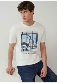 Wit T-shirt met een blauwe grafische afbeelding van een straattaferelen met een vintage voertuig. Het ontwerp bevat verkeerslichten en gebouwen.