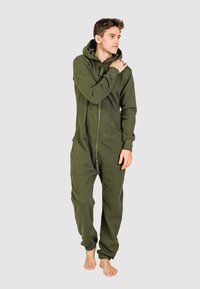 Olijfgroene zip-up onesie gemaakt van zachte stof, met een capuchon, zakken aan de voorkant en elastische boorden. Geen zichtbare patronen of hardware-accenten.