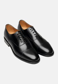 Schwarze Leder-Dressschuhe mit glatter Oberfläche, Kaptoedesign und sechs Ösen. Mit einem kontrastierenden Tan-Innenfutter und einer schlanken Außensohle.