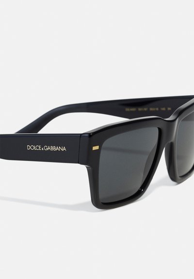 Black acetate sunglasses feature a square frame, grey tinted lenses, and a gold accent on the temple with 'DOLCE & GABBANA' branding.