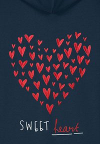 Sweat à capuche bleu marine orné d'un motif de cœurs rouges de différentes tailles au-dessus du texte « SWEET heart » en polices blanches et rouges.