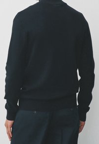 Pull noir en maille avec col montant, poignets et ourlet côtelés. Texture douce, coupe ajustée, uni sans motifs ni accents.