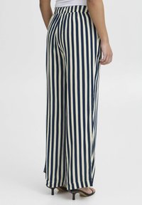 Navy and cream striped wide-leg trousers with a high-waisted design. Smooth fabric texture with a relaxed fit and side slits at the hems.