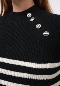 Black and white striped sweater made of textured knit fabric; features a high neckline and silver buttons on the left shoulder.