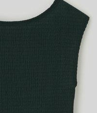 Gros plan sur un tissu texturé vert foncé avec un motif plissé subtil et une large couture d'épaule sur un vêtement.