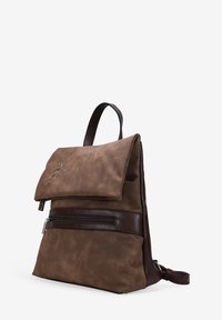 Mochila de cuero marrón con solapa plegable, con bordado. El diseño incluye un bolsillo frontal con cremallera y un acabado texturizado.