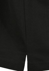 T-shirt en coton noir avec une texture côtelée, des manches courtes et un détail de couture centrale avec une petite fente à l'ourlet.