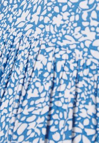 Tecido azul com um padrão floral branco, apresentando um design plissado. A textura parece suave, com uma qualidade leve e respirável.