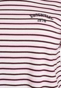 Triibuline heledaruuniline T-särk, mis on valge ja heleroosa toonides tumeroosade joontega, millel on musta värvi tikandiga "ESSENTIAL 1978". Pehme puuvillane kangas.