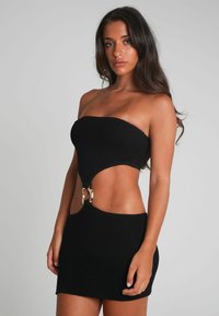 Svart stickad miniklänning med strapless-design, utskärning vid midjan och detaljer i guld. Texturerat tyg och figursydd silhuett.