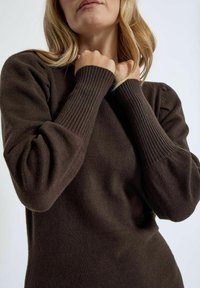 Dark brown knit sweater with ribbed cuffs and balloon sleeves, featuring a soft texture and a fitted silhouette.