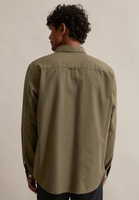 Oliwkowozielona koszula z długim rękawem wykonana z bawełny; posiada tylne karczki i zapinane na guziki mankiety. Gładka tekstura z dopasowanym krojem.