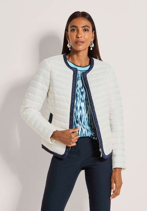 Lichtgewicht doorgestikte jas in off-white met marineblauwe accenten, voorzien van een ronde hals, ritssluiting aan de voorkant en zijzakken. Combinatie met een top met patroon.