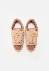 Sneakers atletici beige con una parte superiore in tessuto morbido, dettagli in camoscio, punta rotonda e lacci piatti. Presentano un collo imbottito e un logo sulla linguetta.