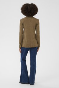 Khaki Rollkragenpullover mit langen Ärmeln, kombiniert mit ausgestellten blauen Denim-Jeans. Der Stoff wirkt weich; die Jeans zeigen eine klassische Denim-Struktur.