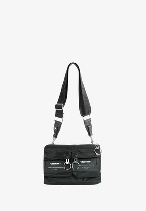 Bolso de hombro negro hecho de nailon con herrajes plateados. Cuenta con dos bolsillos frontales, una cremallera superior y una correa desmontable.