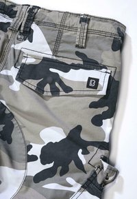 Shorts de camouflage en gris et noir. Fabriqués en tissu léger avec une poche arrière comportant une petite étiquette noire. Coutures visibles en accent.