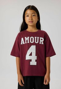 T-shirt en coton bordeaux avec "AMOUR" et le numéro "4" en clous argentés. Manches courtes, coupe décontractée, col rond.