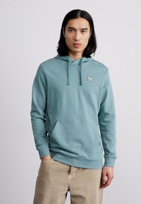 Felpa leggera color verde acqua con tasca a marsupio, cordoncino e un piccolo logo sul petto. Tessuto morbido con maniche lunghe e polsini a coste.