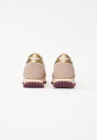 Baskets en suède rose avec des accents dorés, forme arrondie et semelle texturée. Présente la marque "Blauer USA" sur le talon.