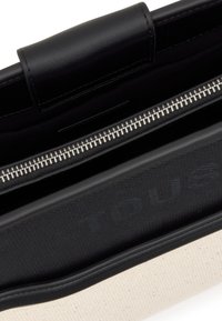 Czarna skórzana torebka z beżową, materiałową podszewką, wyposażona w srebrny zamek błyskawiczny i wytłaczane logo na jednej stronie. Gładka faktura i usztywniona konstrukcja.