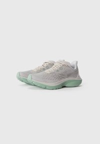 Une paire de chaussures de course gris clair avec des détails texturés et des semelles vert menthe sur un fond blanc uni.