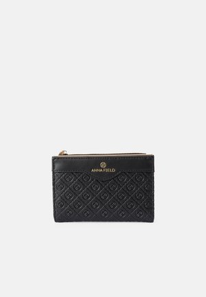 Black wallet featuring a quilted design with embossed patterns, gold-tone logo, and a zip closure. Made from synthetic material.