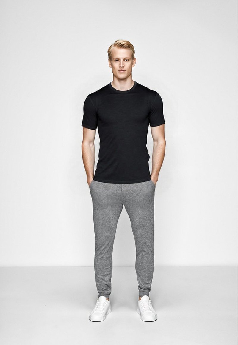 Sort bomulds T-shirt med korte ærmer, parret med lysegrå sweatpants og hvide sneakers. Glat tekstur, afslappet pasform og minimalistisk design.