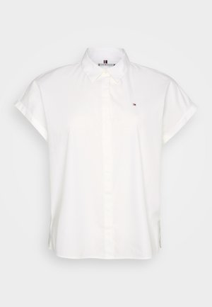 White short-sleeve shirt with a collar, featuring a front button closure and a small logo on the chest. Smooth fabric, tailored fit.