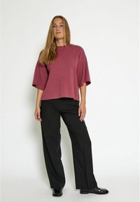 Magenta cropped knit top with short sleeves paired with black wide-leg trousers; smooth texture, relaxed fit, and minimalist design.