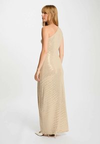 Abito lungo beige con una spalla decorato con paillettes, dalla silhouette aderente, superficie texturizzata e una leggera lucentezza. Retro liscio con dettagli discreti.