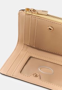 Intérieur de portefeuille en cuir beige rosé avec une fermeture éclair, des emplacements pour cartes, une fenêtre d'identification transparente et des accents de quincaillerie dorée. Détails de couture texturée.