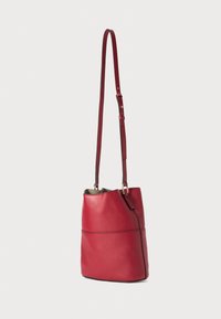 Sac seau en cuir rouge avec une texture lisse, une bandoulière réglable et des accents en métal doré. Fond arrondi et design à ouverture sur le dessus.