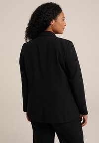 Černý blazer s přizpůsobeným střihem, dlouhými rukávy, zapínáním na jeden knoflík a mírně rozparkem vzadu, vyrobený z hladkého, lehkého materiálu.