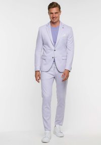 Blazer lavanda claro y pantalones a juego hechos de una tela texturizada. Acompañado de una camiseta lavanda y zapatillas blancas.