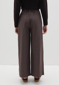 Pantalones de pierna ancha a cuadros marrones con cintura elástica fruncida, que presentan un sutil patrón de tartán y una textura de tela fluida.