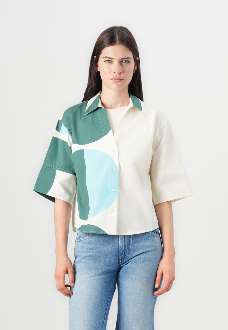 Chemise à manches courtes avec un mélange de couleurs vert, bleu clair et crème, ornée de motifs géométriques ; en coton avec un devant à bouton.