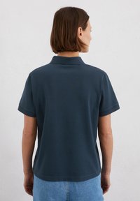 Marineblauwe polo in zachte katoen met korte mouwen en een klassieke kraag. Heeft een rechte snit en een eenvoudig ontwerp, zonder zichtbare patronen.