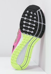 Suola di scarpa da corsa rosa con battistrada nero, intersuola verde neon, supporto per l'arco bianco e lacci visibili su sfondo bianco.