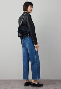 Svart skinnjacka, blåa högmidjade jeans och svarta loafers. En liten svart mockaväska med silverkedja fulländar outfiten.