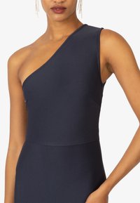 Robe navy à une épaule en tissu côtelé. Présente un corsage ajusté, des détails en panneaux latéraux et une texture lisse.