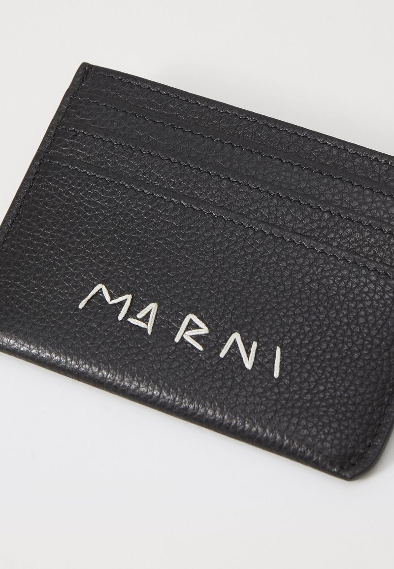 Portafoglio in pelle nera con tre slot per carte, finitura testurizzata e logo "MARNI" in bianco a rilievo. Design compatto e minimalista.