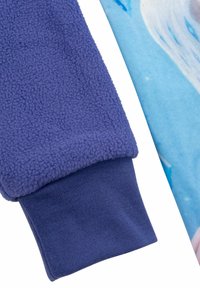 Manica in pile viola con una superficie testurizzata, abbinata a un tessuto liscio e colorato che presenta un design astratto blu e bianco.