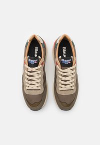 Sneakers med en blanding av brune, grønne og brune materialer, med kremfargede snøringer, polstret krage og en logo på tungen.